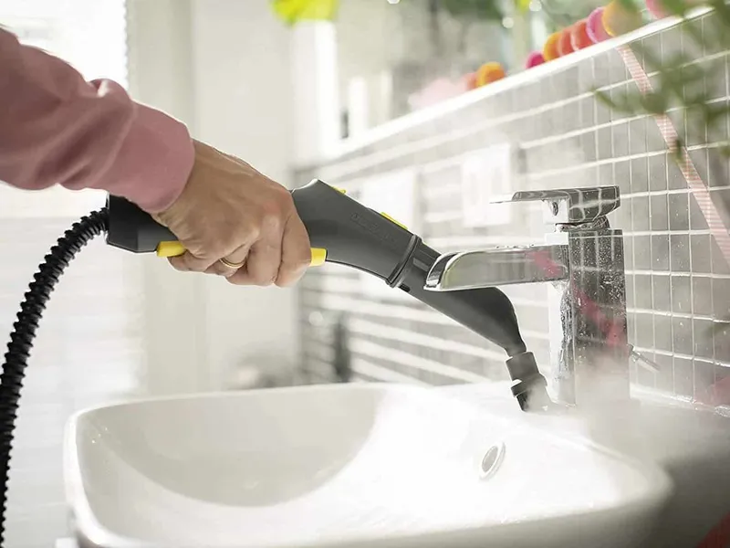 Cleaning bathroom tap with a steam cleaner