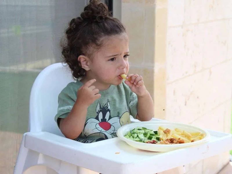 Toddler eating pasta and vegetables