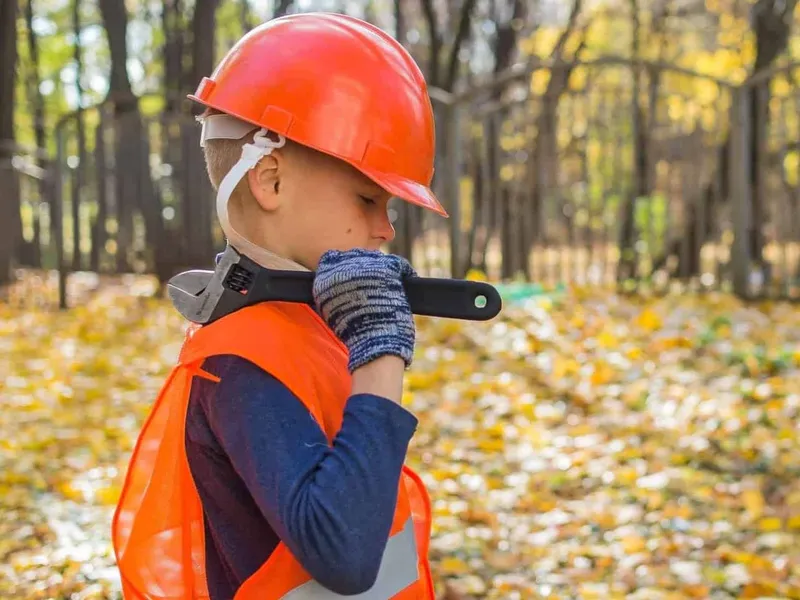 Young boy wearing hi-vis gear with wrench