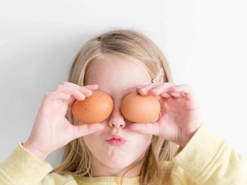 Girl holding two eggs in front of her eyes