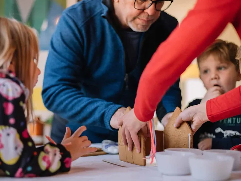 Grandparents and grandkids building a gingerbread house