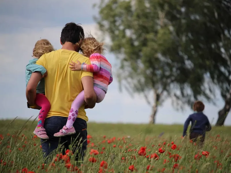 Parent and children walking through a flower meadow